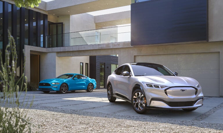 2025 Ford Mustang Mach-E and Mustang parked in driveway